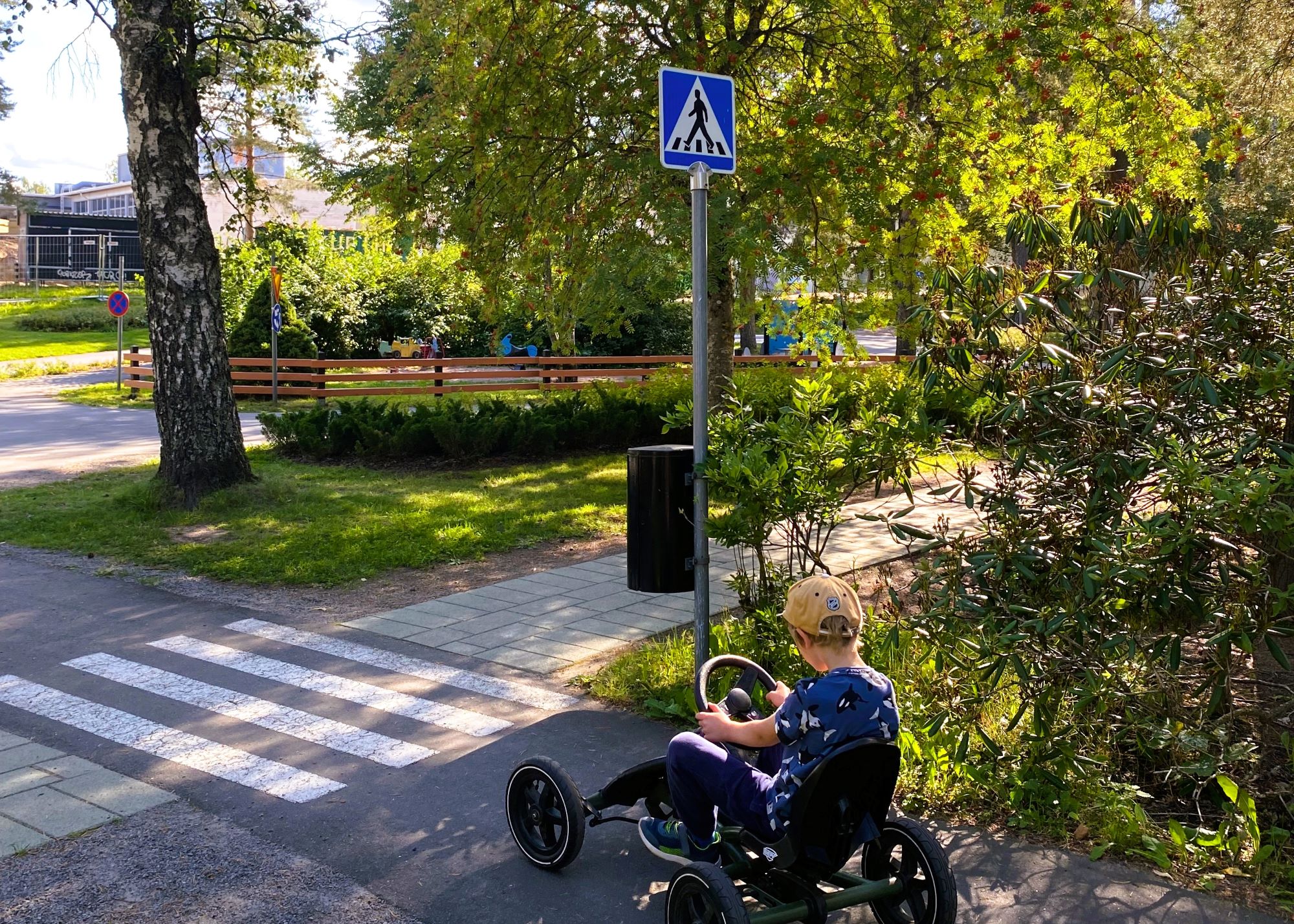 Lasten liikennekaupunki kesällä, poika ajaa polkuautolla.